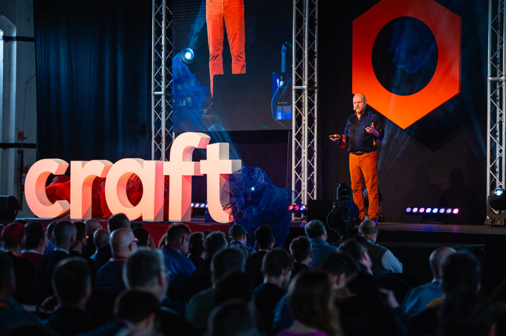 Speaker presenting on stage at Craft Conference with a large audience and illuminated ‘craft’ sign in Budapest